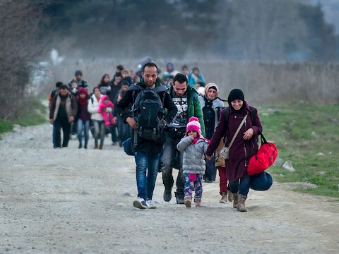 Vluchtelingen uit Syrië en Irak steken de grens tussen Griekenland en Macedonië over.
