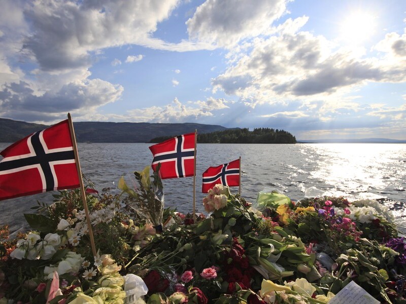 Noorse vlaggen en bloemen eren de slachtoffers nabij het eiland waar het bloedbad plaatsvond.