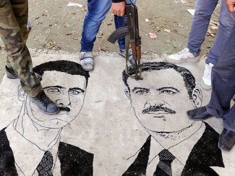 Een afbeelding van president Assad en zijn vader Hafez, de vorige president van Syrië, worden vertrapt.