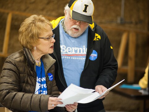 Aanhangers van Bernie Sanders onderzoeken stemformulieren vooraleer ze aan de caucus beginnen in de brandweerkazerne van Jackson Township, Keokuk, Iowa.
