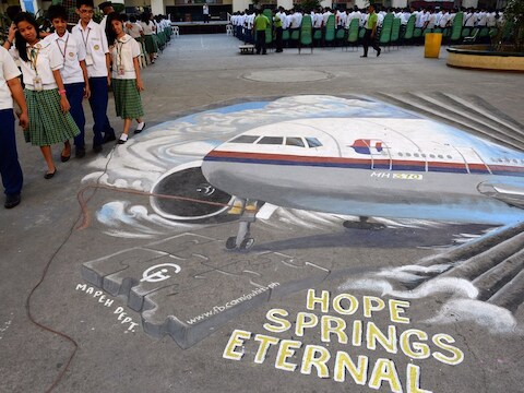 Scholieren wandelen naast een muurtekening van de vermiste Malaysia Airlines-vlucht MH370.
