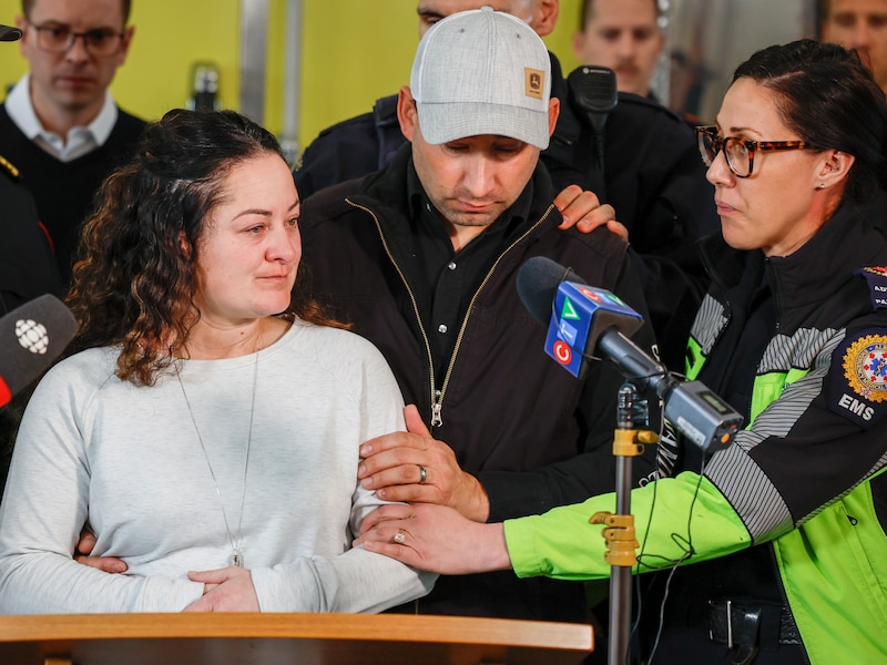 Ambulancier Jayme Erickson (links) wordt tijdens een persconferentie getroost door haar echtgenoot Eric en een vriendin.