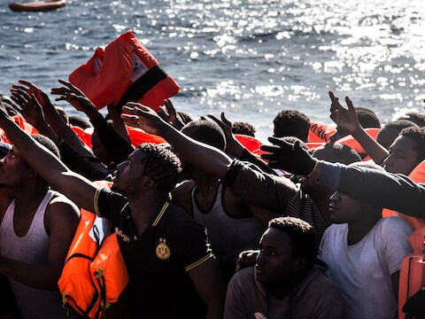 Migranten op weg naar Italië krijgen reddingsvesten aangereikt vanop een reddingsboot van Artsen Zonder Grenzen en SOS Mediterranee.