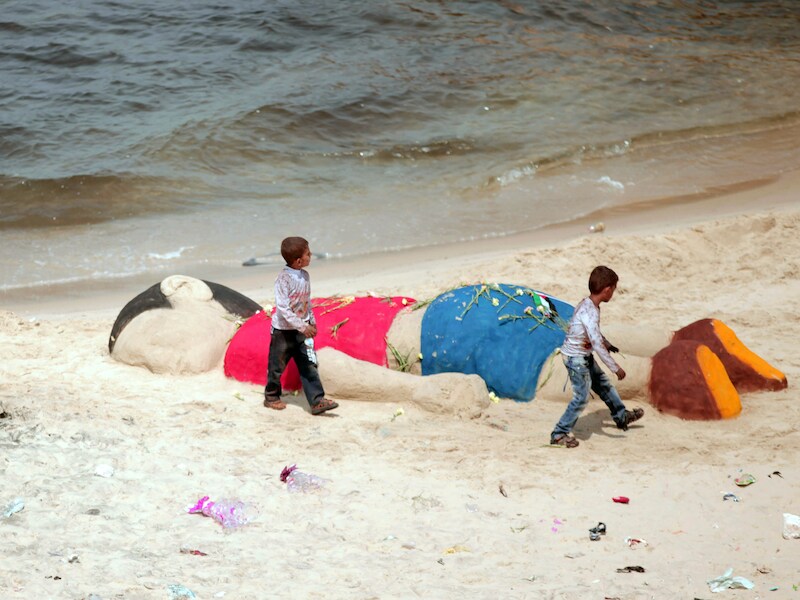 Palestijnse jongetjes bij de zandsculptuur van Aylan in Gaza.