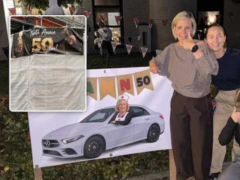Ann met haar twee collega’s Dien en Jennifer bij de versiering die ze aanbrachten voor haar vijftigste verjaardag. Inzet: het spandoek dat Ann vanmorgen aan de steigers van de kerk van Arendonk zag hangen.