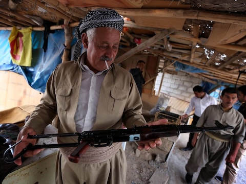 Een Koerdische man inspecteert de koopwaar op een wapenmarkt in Irak.