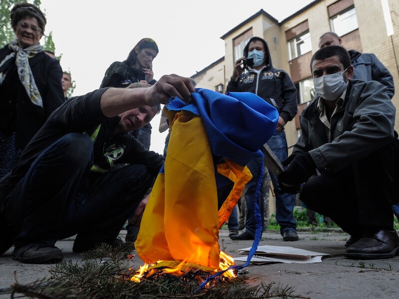 Pro-Russische demonstranten steken in de stad Donetsk de Oekraïense vlag in brand.