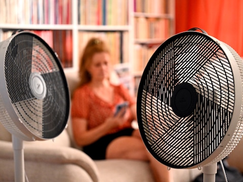 Een vrouw probeert tijdens de hittegolf haar omgeving koel te houden met ventilatoren.