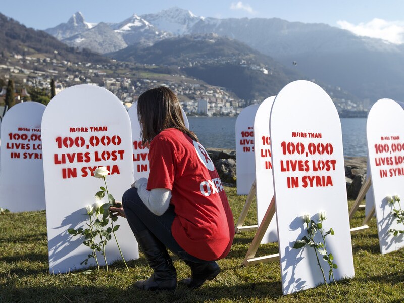 Een Oxfam-medewerker legt witte rozen bij symbolische grafstenen voor de slachtoffers in Syrië.