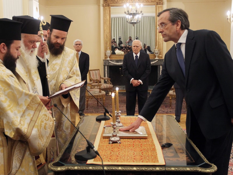 Antonis Samaras wordt ingezworen door de aartsbisschop van Athene. President Papoulias kijkt toe.