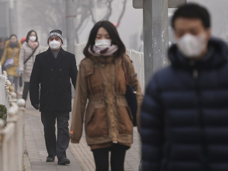 Inwoners van Peking dragen mondkapjes op straat.