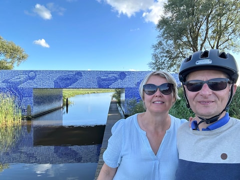 Burgemeester Lieve Castryck en haar man Koen Blomme tijdens een fietsvakantie in Friesland aan het monument voor de Elfstedentocht.