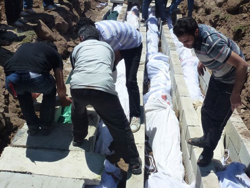 Syrische burgers aan het massagraf van meer dan honderd slachtoffers die in Houla geëxecuteerd werden.