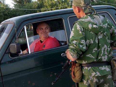 Een gewapende pro-Russische militant spreekt met een bestuurder nabij de grens tussen Rusland en Oekraïne.