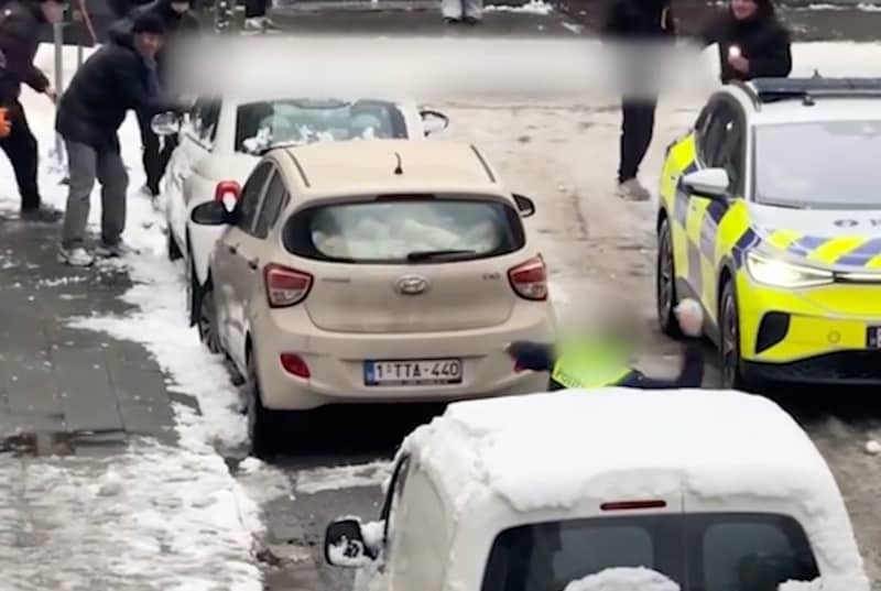 Een agent legt aan met een stevige sneeuwbal in de Prekersstraat in Antwerpen, tijdens een ludiek gevechtje met jongeren.