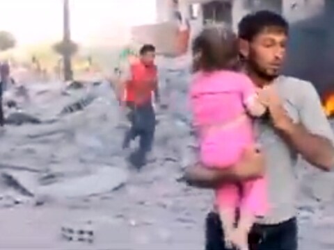 Een Syriër draagt een gewond meisje weg na een aanval in Raqqa.