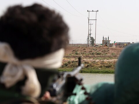 Een Iraakse strijder kijkt naar het niemandsland tussen waar Iraakse troepen zijn gelegerd en rebellen van ISIS in Taaza, op 25 kilometer van Kirkoek.