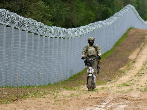 Archiefbeeld. Een Letse militair patrouilleert langs versterkte hekken aan de grens tussen Letland en Wit-Rusland. 