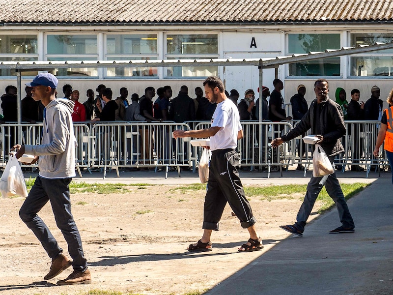 Asielzoekers staan in de rij voor de voedselbedeling door 'Vie Active' in het kamp in Calais.