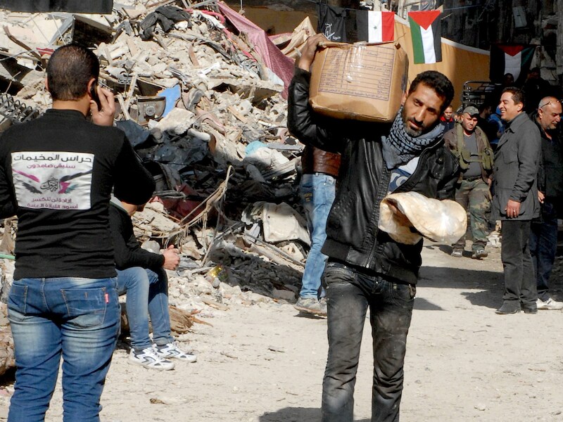 Een inwoner van Yarmouk draagt levensmiddelen met zich mee.