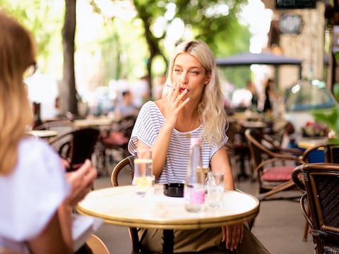Illustratiebeeld van een vrouw op terras met een sigaret.