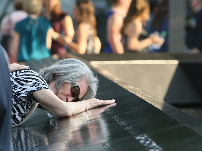 Mija Quigley vleit zich op de naam van haar zoon Patrick Quigley op de gedenksteen aan het nieuwe One World Center in New York. Quigley was een passagier op het eerste vliegtuig dat zich in het World Trade Center boorde.