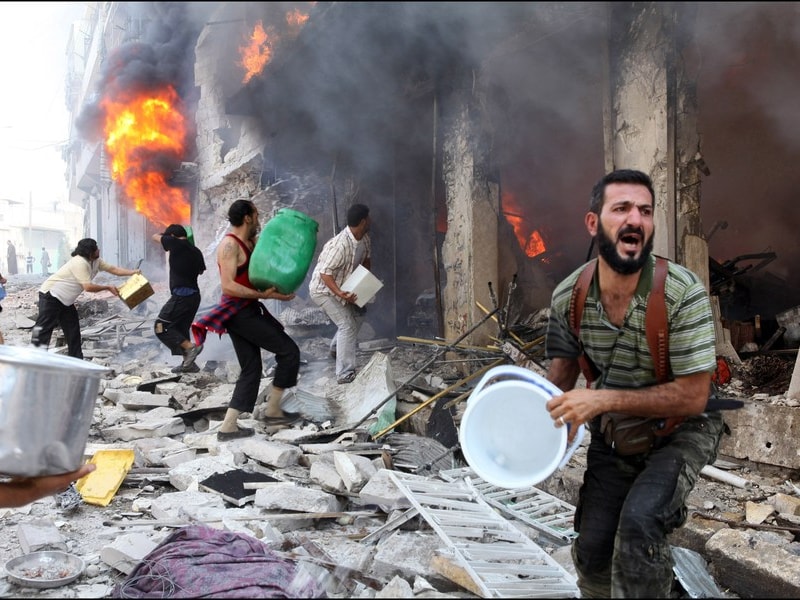 Burgers proberen het vuur te blussen nadat het Syrische leger een appartementsblok bombardeerde.