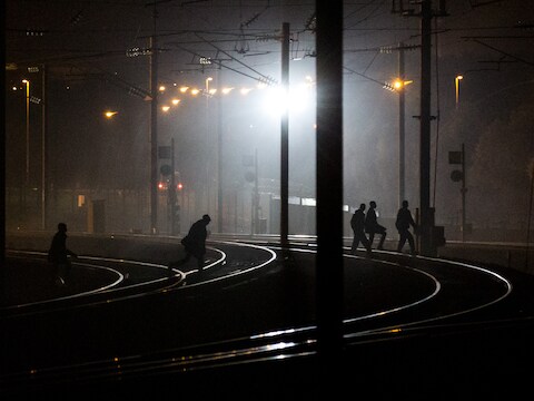 Vluchtelingen wandelen over de treinsporen in de buurt van de Eurotunnel in Calais