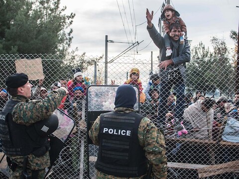 Asielzoekers protesteren achter het hek aan de Grieks-Macedonische grens, vandaag.