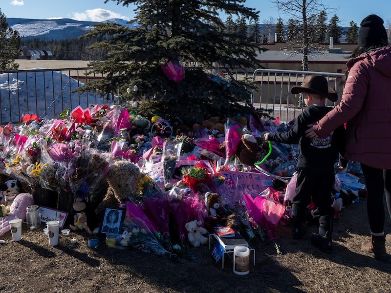 Een moeder en haar kind staan bij de bloemenzee voor de slachtoffers in Tumbler Ridge.