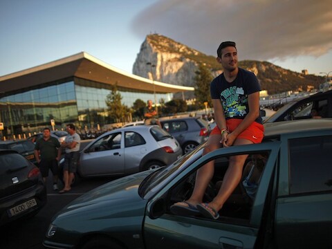 Een chauffeur wacht op het dak van zijn auto tot hij vanuit Gibraltar Spanje in mag.
