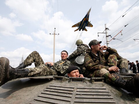 Een gevechtsvliegtuig vliegt boven Oekraïense soldaten.