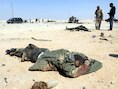 Libische rebellen staan naast de lichamen van twee Kadhafi-huurlingen.