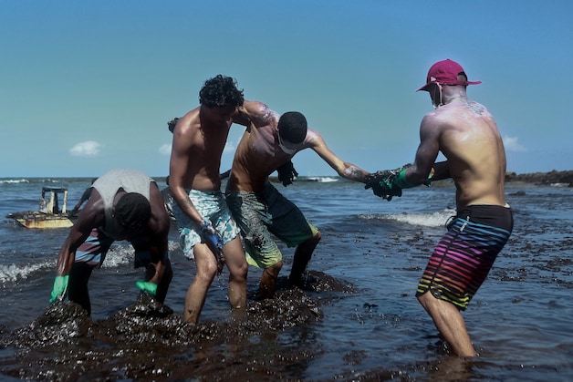 Vrijwilligers zitten onder de olie terwijl ze die proberen te verwijderen uit de zee bij Cabo de Santo Agostinho in de staat Pernambuco.