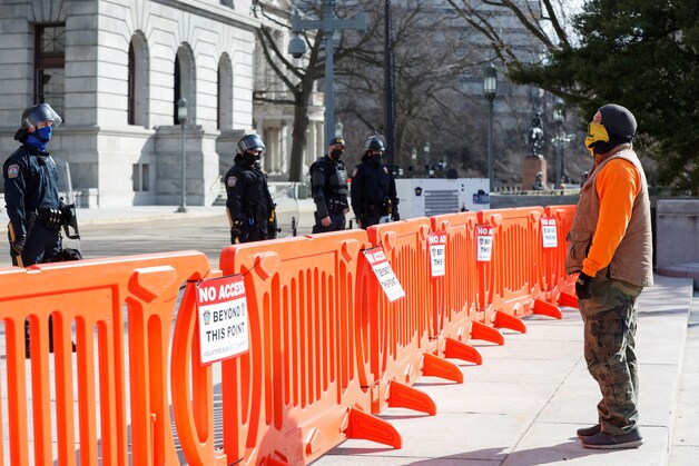 Politieagenten bewaken het State Capitol van Pennsylvania in Harrisburg, rechts een pro-Trumpaanhanger.