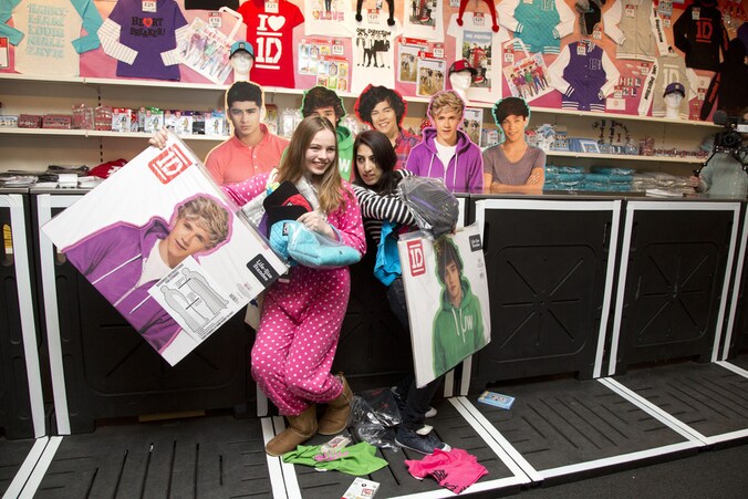 Fans van One Direction in een winkel met merchandise van de groep.