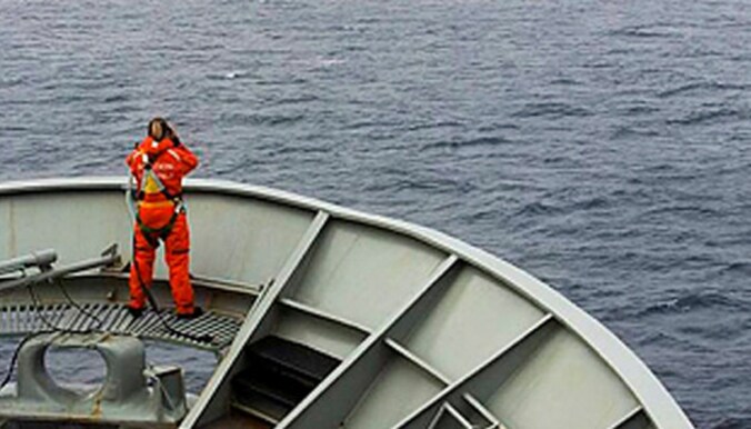 Een bemanningslid van de HMAS Success tuurt in het zuiden van de Indische Oceaan naar brokstukken van vlucht MH370