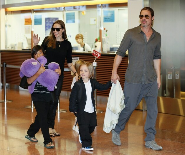 Angelina Jolie (links) en Brad Pitt (rechts) op een vliegveld met hun kinderen Pax Thien, Shiloh en Knox.