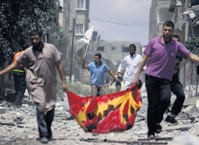 Een groep Palestijnen ontvlucht de wijk Shijaiyah in Gaza-Stad. Een van de mannen houdt een witte vlag in de hand in de hoop dat de groep niet wordt aangevallen.