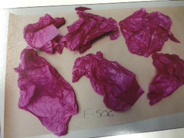 Stukjes roze inpakpapier zijn bewijsmateriaal. De verdachte zou lichaamsdelen met het papier naar basisscholen hebben gestuurd.