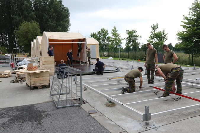 Militairen trekken de mobiele wooneenheden op naast het asielcentrum.