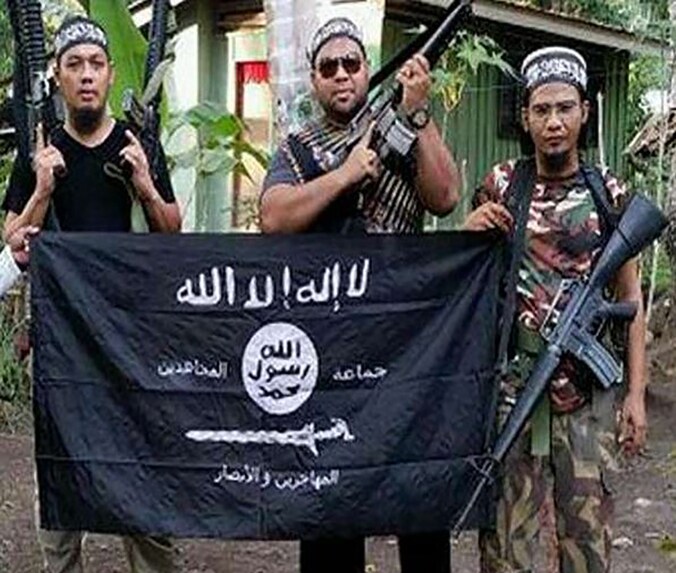 De Maleisische militanten Mahmud Ahmad, Muhammad Joraimee Awang Raimee en Muamar Gadafi poseren met IS-vlag.