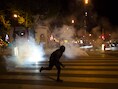 Een demonstrant rent weg in Parijs nadat de politie wolken traangas verspreid. In de Franse hoofdstad zijn na de uitslag van de eerste ronde van de presidentsverkiezingen mensen de straat opgegaan.
