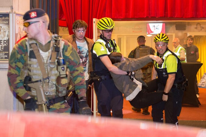 Een slachtoffer wordt uit de zaal gered terwijl een militair de wacht houdt.