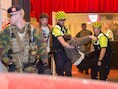 Een slachtoffer wordt uit de zaal gered terwijl een militair de wacht houdt.