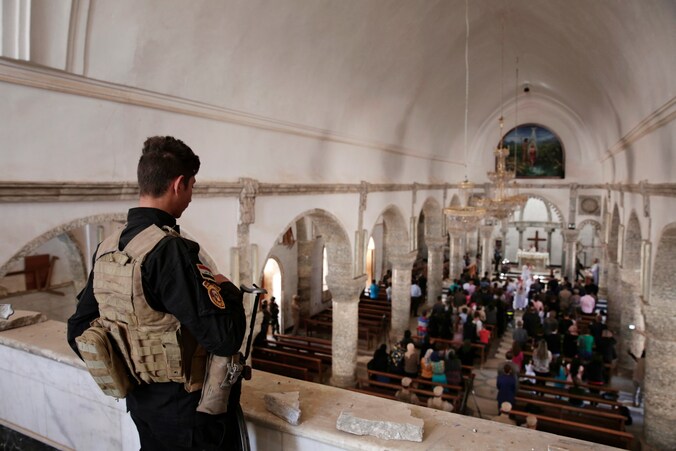 Een militair houdt de wacht tijdens de paasmis in Qaraqosh, Irak. 
