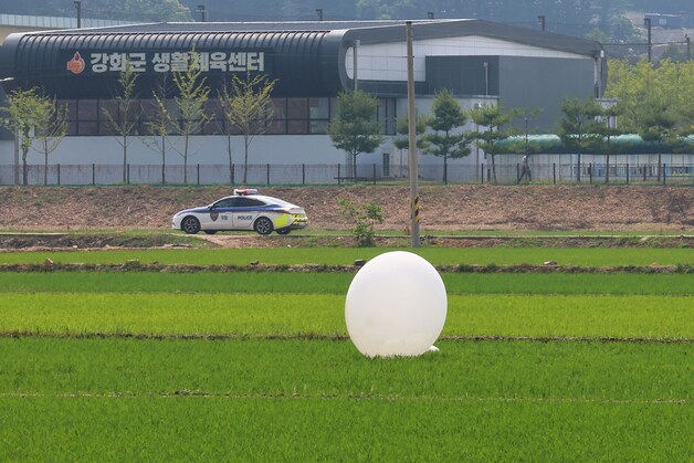 Een Zuid-Koreaanse politieauto rijdt langs een veld nabij Incheon waarin een Noord-Koreaanse ballon geland is.