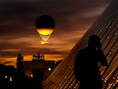 Een man maakt een foto van de piramide bij het Louvre met op de achtergrond de olympische vlam die opstijgt vanuit de Tuilerieën.