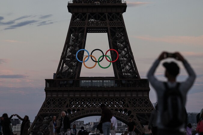 Toeristen nemen foto's van de olympische ringen op de Eiffeltoren in Parijs.