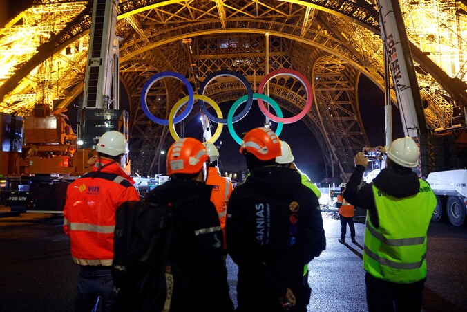 Werklui halen de olympische ringen van de Eiffeltoren.